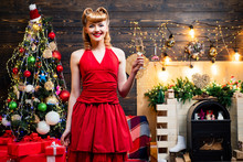 Retro Woman With Retro Curly Hair Near The Christmas Tree. Young Woman In Red Dress Celebrating New Year Or An Event.