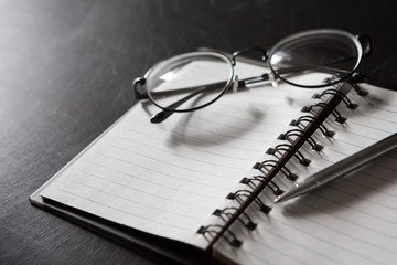 Wall Mural - Selective focus of Pen, notebook, glasses, on black background and  copy space