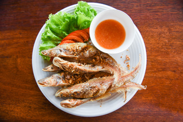 Wall Mural - fried fish with vegetable salad tomato and sauce on white plate wooden table - freshwater fish Mekong River Other names Sheatfishes Siluriformes Siluridae