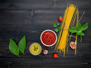 Wall Mural - The thin spaghetti on black wooden background. Yellow italian pasta with ingredients. Italian food and menu concept.