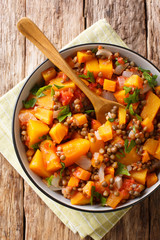 Wall Mural - Homemade pumpkin ragout with lentils, onions and carrots in a bowl close-up. Vertical top view