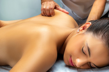 Hand applying pressure on young woman's shoulder blade.