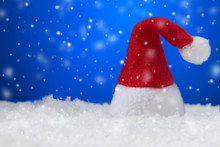 Santa Claus Hat On Blue Snowing Background With Copy Space