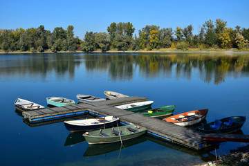 Autumn landscape with a lake, a boat bridge and some boats.