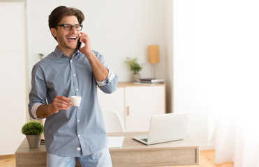 Poster - Excited man talking by cellphone drinking coffee standing in office