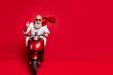 Poster - Full length photo of cheerful old man in eyewear eyeglasses showing rocker sign driving his bike wearing white sweater isolated over red background