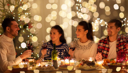 Canvas Print - holidays and celebration concept - happy friends having christmas dinner at home and drinking red wine