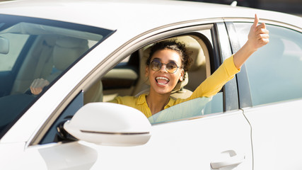 New car owner. Happy woman showing thumb up