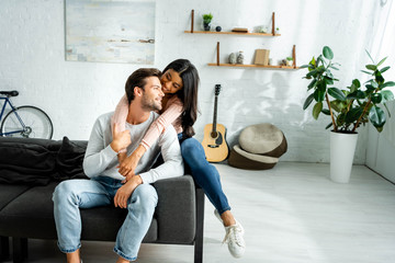 african american woman and handsome man smiling and hugging in apartment