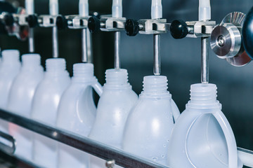 Wall Mural - white plastic gallons or bottle on the production line of the conveyor at filling machine in the factory. selective focus. industrial and technology concept.