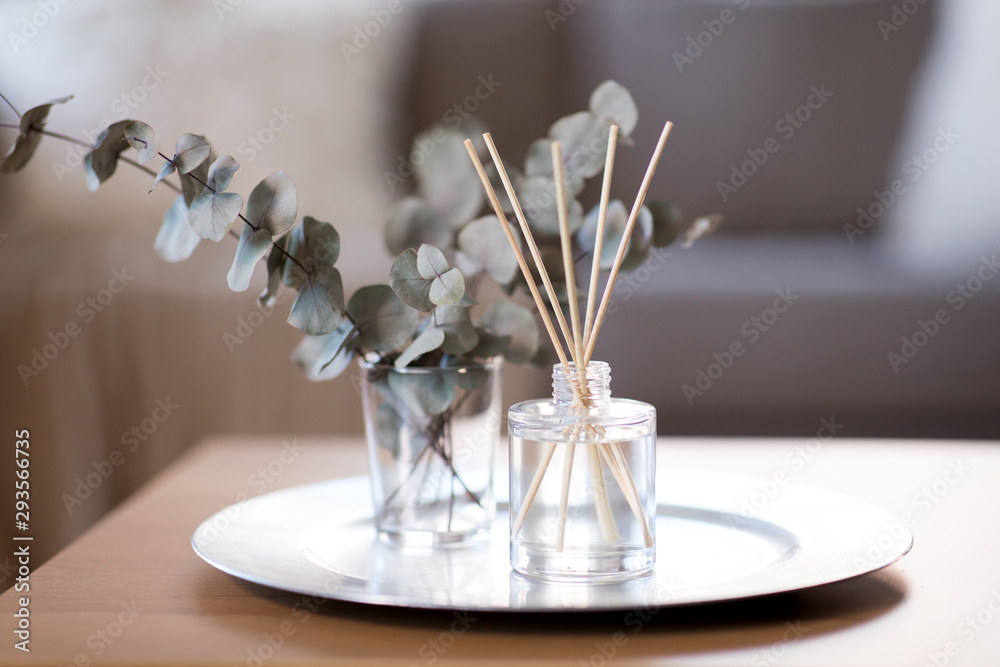 decoration, hygge and aromatherapy concept - aroma reed diffuser and branches of eucalyptus populus on table at home - obrazy, fototapety, plakaty 