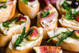 Fototapeta Lawenda - Traditional tapas from spain or italian bruschetta with cheese, meat and figs. Party food on catering platter.