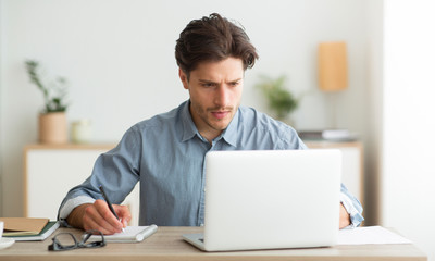 Poster - Young Entrepreneur Working On Laptop And Taking Notes Indoor