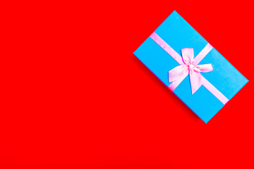 Poster - blue gift box with pink ribbon on a red background.