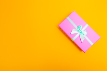 Poster - pink box with a ribbon on a yellow background.