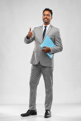 Wall Mural - business, office worker and people concept - smiling indian businessman in shirt with tie showing thumbs up over grey background