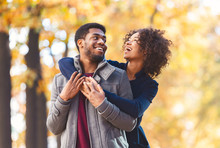 Portrait of sweet afro couple cuddling over autumn background