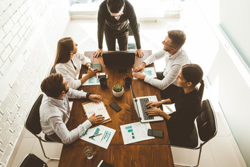 A team of young businessmen working and communicating together in an office. Corporate businessteam and manager in a meeting.