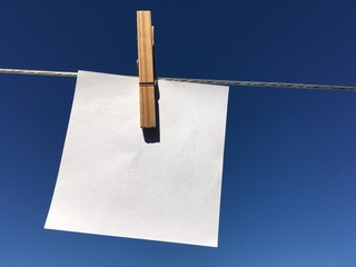 Photo of a white paper, clipped with a clothes pin to a metal string.  Paper note, graphics for a business presentation.