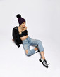 © Dmitry Lobanov - Glamorous grunge woman in torn jeans, leather top and jacket, winter hat and silver brutal shoes sitting on white floor