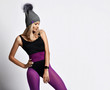© Dmitry Lobanov - Athletic blonde girl in purple sports wear, gray winter hat and with smart watches standing with one leg to the side