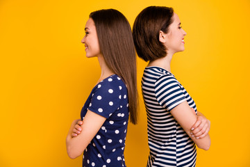 I am taller than you. Profile photo of two amazing ladies standing back-to-back measuring height wear summer casual t-shirts isolated yellow background