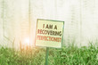 © Zofia - Conceptual hand writing showing I Am A Recovering Perfectionist. Concept meaning Obsessive compulsive disorder recovery Plain paper attached to stick and placed in the grassy land