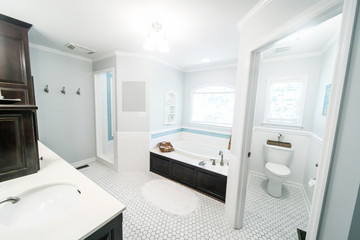 1950's style bathroom with tile floor and dark brown cabinets in white and blue accents wit a window and natural light