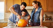 Hispanic American Family Carving Pumpkin Into Jack O Lantern At Home