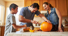 Hispanic American Family Carving Pumpkin Into Jack O Lantern At Home