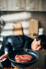 Wall Mural - Chef frying ribeye steak in a pan