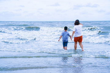 Little boy with mother running to the sea wave