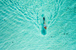 Top down view of a girl swimming in a lagoon. Aerial view of slim woman floating on the water. Summer vacation concept