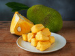 Ripe jackfruit flesh in a white plate on a wooden table for tropical fruit or meat substitute concept.