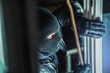© AA+W - Masked burglar with torch and crowbar breaking and entering into a house - shot with dramatic motion