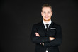 © Arunporn - Portrait of young smart and handsome business man in black suit standing on isolated black background.