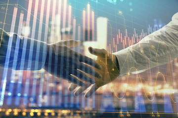 Double exposure of financial chart on cityscape background with two businessmen handshake. Concept of financial analysis and investment opportunities