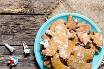 Wall Mural - Homemade Decorated Gingerbread Men Cookies on a plate on rustic aged wooden table and vintage Christmas toys. Flat lay view.