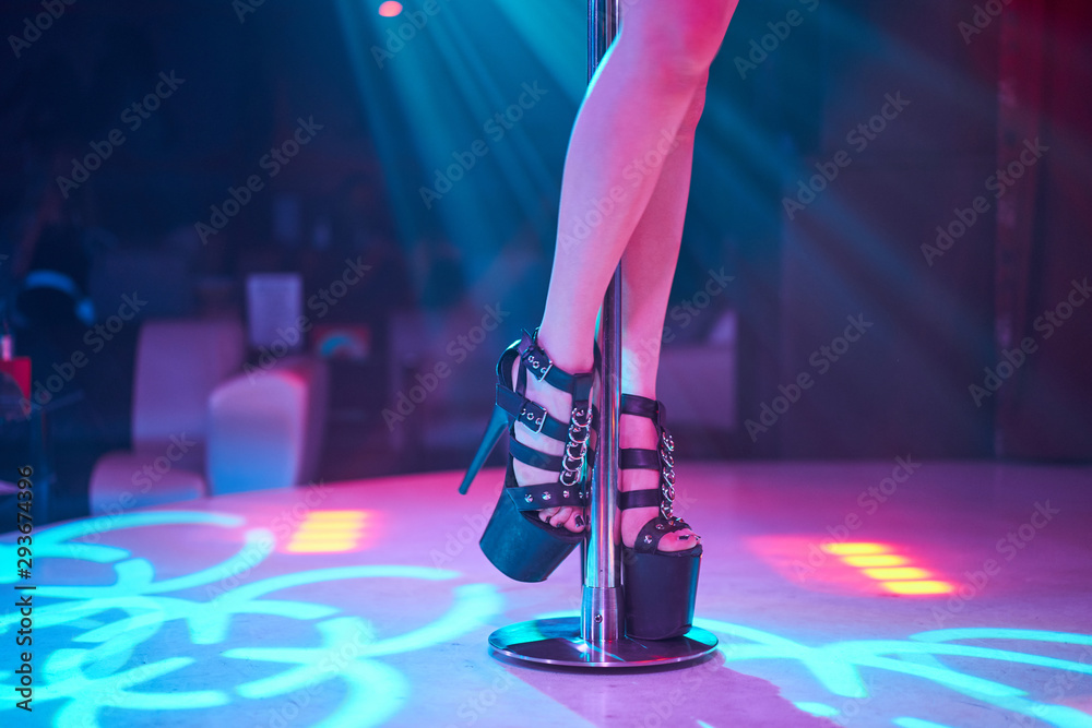 Young sexy woman pole dancing striptease with pylon in night