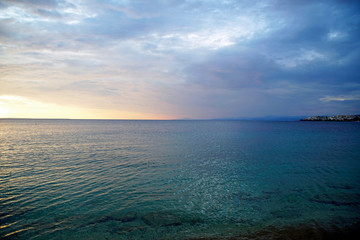       Horizontal shot. Empty beach in the evening at sunset. . Silhouettes and coastline. Sea bright sky. Greece Sithonia. Horizon. Clouds and rays of the sun. Bird island  