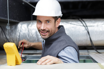 male technician repairing industrial air conditioner indoors