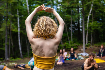 Wall Mural - Diverse people enjoy spiritual gathering A young healthy and free spirited woman is seen practicing mindful dance amongst a group of people meditating during a multicultural celebration in nature.