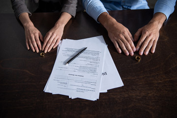 Wall Mural - partial view of couple at table with divorce documents and rings