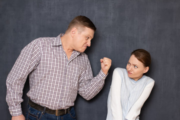 Wall Mural - Angry man is shaking clenched fist before frightened woman