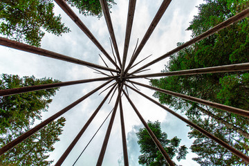 Poster - Diverse people enjoy spiritual gathering A worm's eye view of a tall teepee (tipi) structure, constructed amongst tall trees at a sacred site dedicated to shaman and native worship.