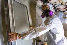 Indoor Damp & Air Quality (IAQ) Testing. A Building Inspector Is Seen At Work Inside A Condemned Building, Removing Glass Panels From A Basement Plagued With Black Mold Spores (aspergillus).