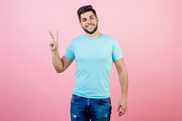 happy smiling handsome bearded man showing two fingers isolated over pink