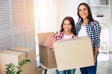 Wall Mural - Together we are strong. Happy family of mother and daughter enjoys new apartment holding together a big cardboard box.