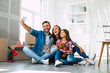 © My Ocean studio - Like in a fairy tale. Young family of father, mother and daughter are sitting on the floor in the a new apartment laughing and taking a selfie together.
