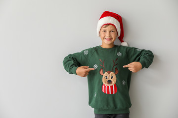 Sticker - Funny boy in Christmas sweater and Santa hat on light background